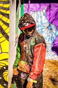 a man wearing a hooded sweatshirt standing in front of a colorful wall