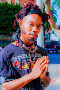 a man with dreadlocks standing on a street
