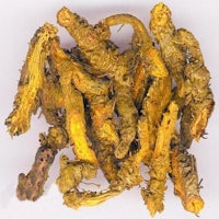 a pile of yellow dried herbs on a white surface
